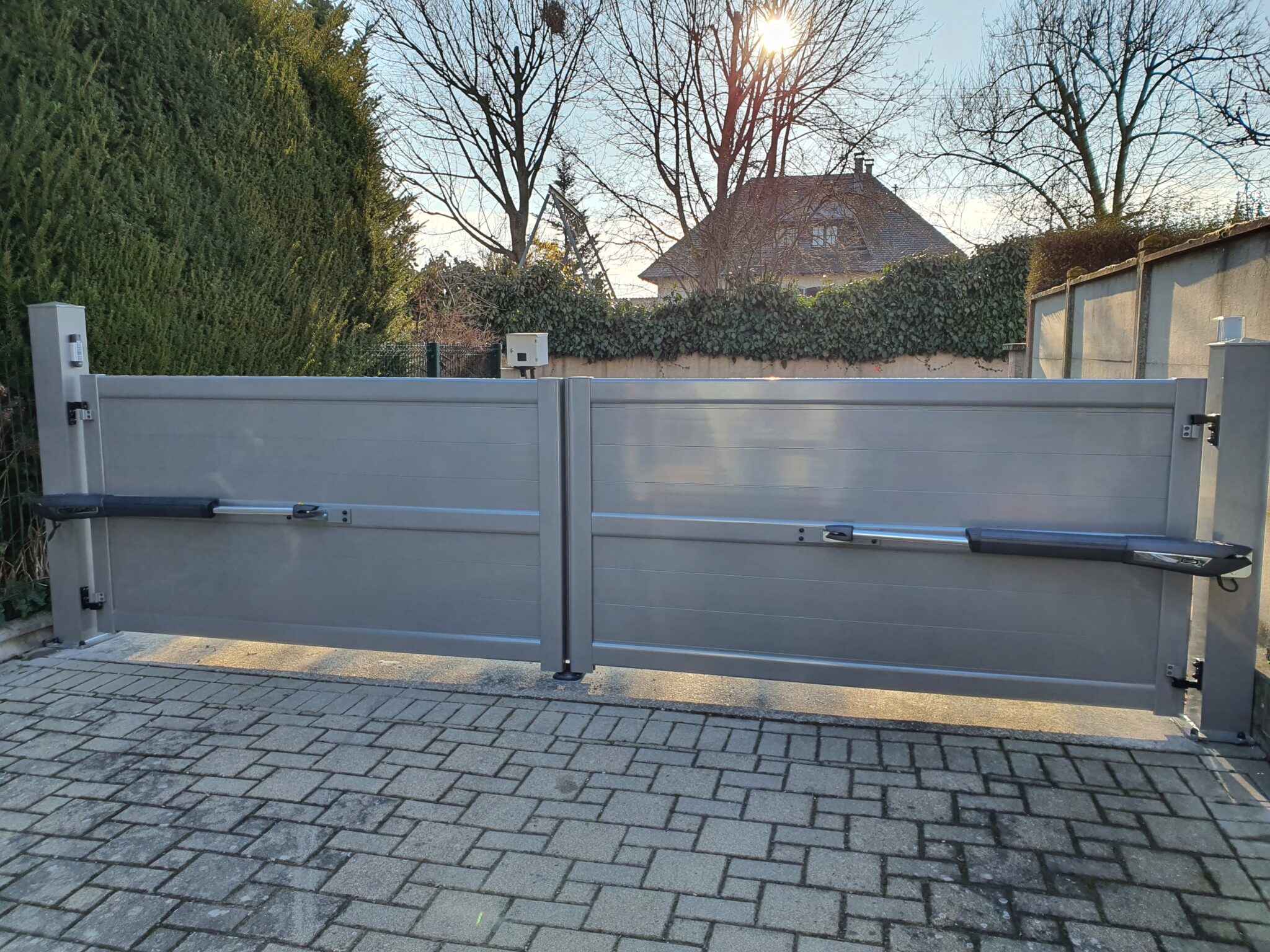 Vue intérieure des bras de motorisation sur un portail battant en aluminium gris pour un automatisme fiable et sécurisé.