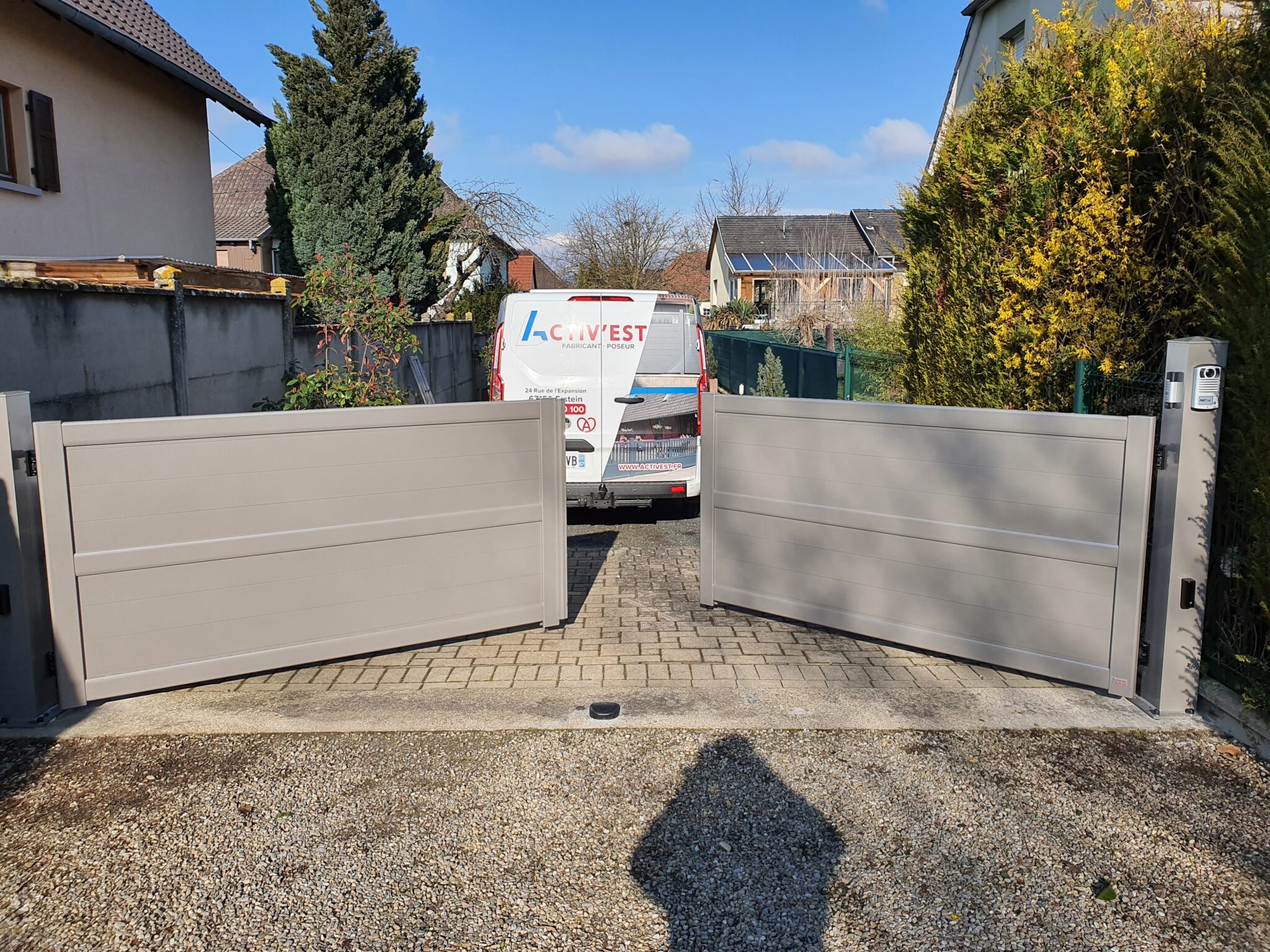 Portail deux battants en aluminium gris avec motorisation invisible et système de visiophone intégré pour un accès sécurisé à Nordhouse.