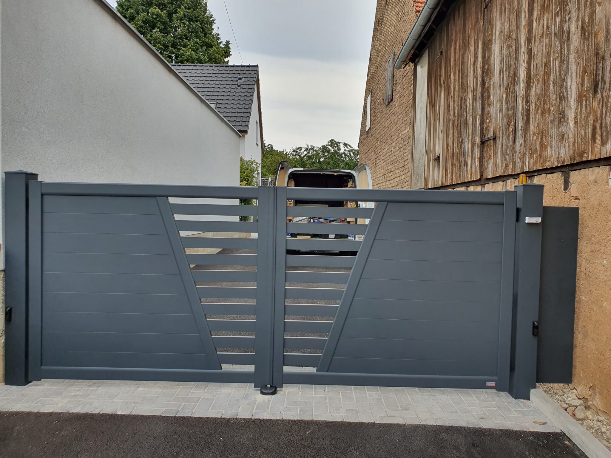 Portail double battant motorisé en aluminium RAL 7031 Gris Bleu avec bandeau central ajouré à Witternheim.