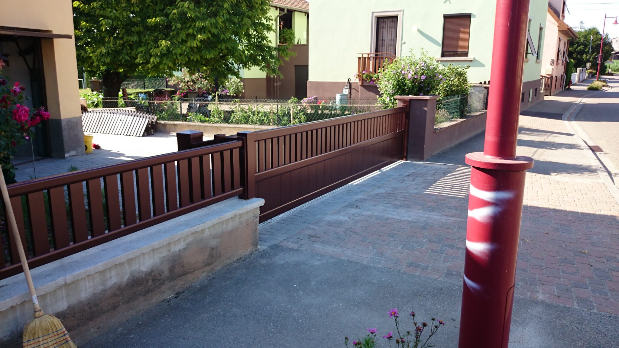 Installation d'un portail coulissant en aluminium RAL 8019 (Gris brun) avec soubassement plein et lames horizontales ajourées, avec clôture assortie.