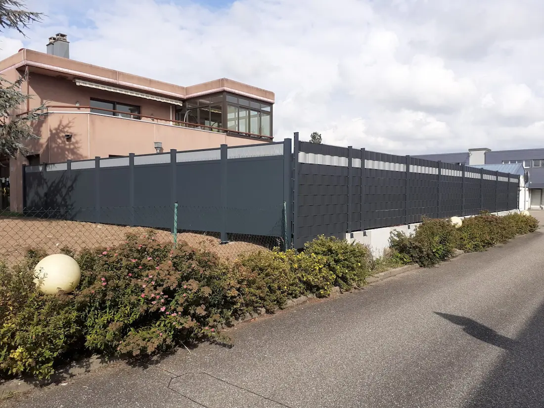 Clôture en treillis rigide avec lamelles occultantes PVC bicolores : vue en angle d'une installation à Osthouse