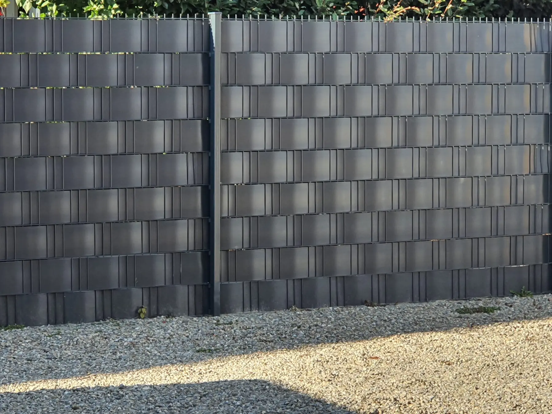Gros plan sur la finition de haute qualité des lamelles occultantes en PVC tressées dans une clôture en grillage rigide installée à Benfeld