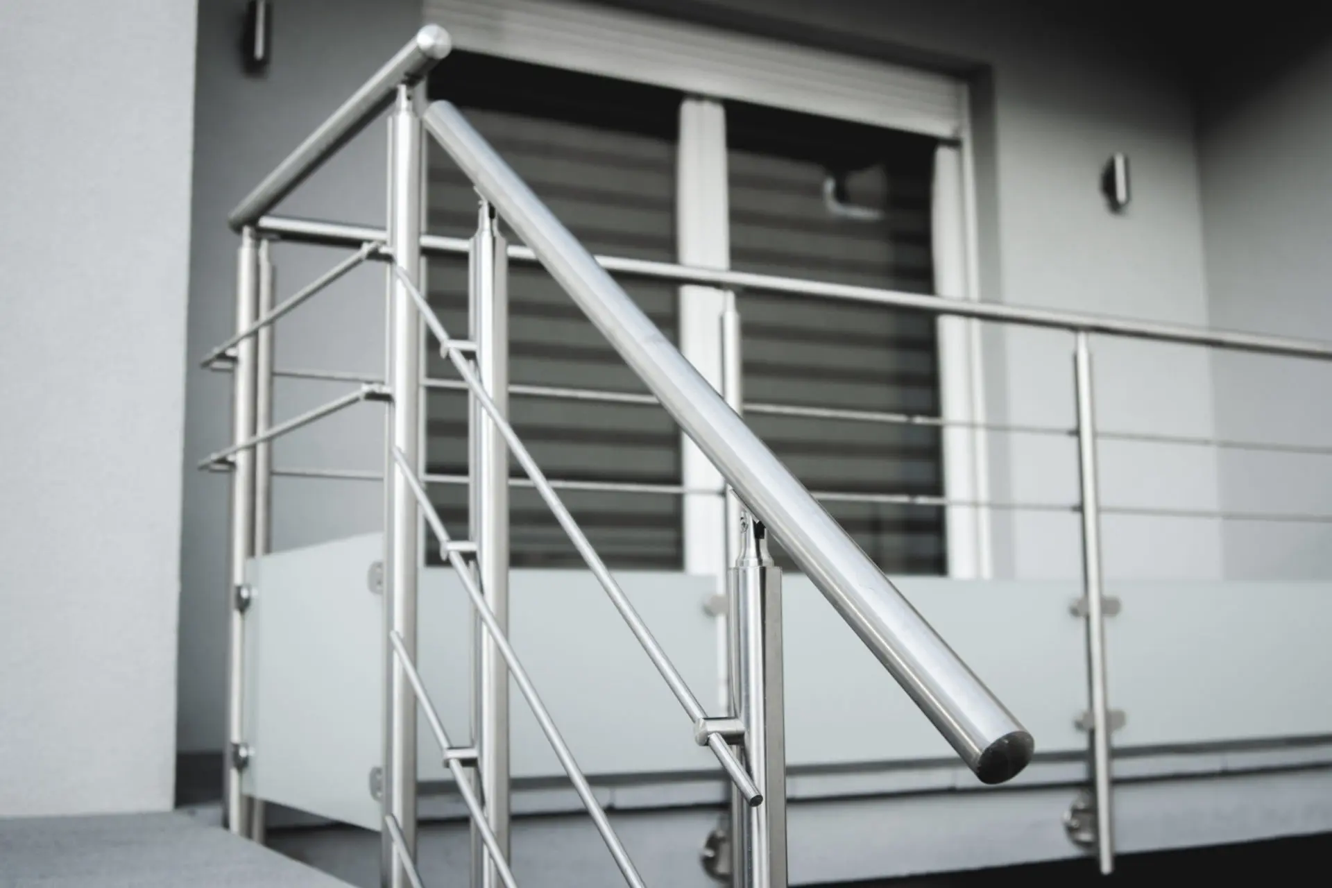 Zoom sur les finitions d'un garde-corps en aluminium brut avec soubassement en verre dépoli, alliant robustesse industrielle et élégance contemporaine à Barr.