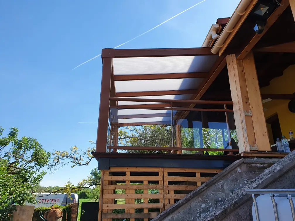 Aménagement extérieur haut de gamme en Alsace combinant un garde-corps vitré et une pergola design en aluminium pour une terrasse moderne et protégée.