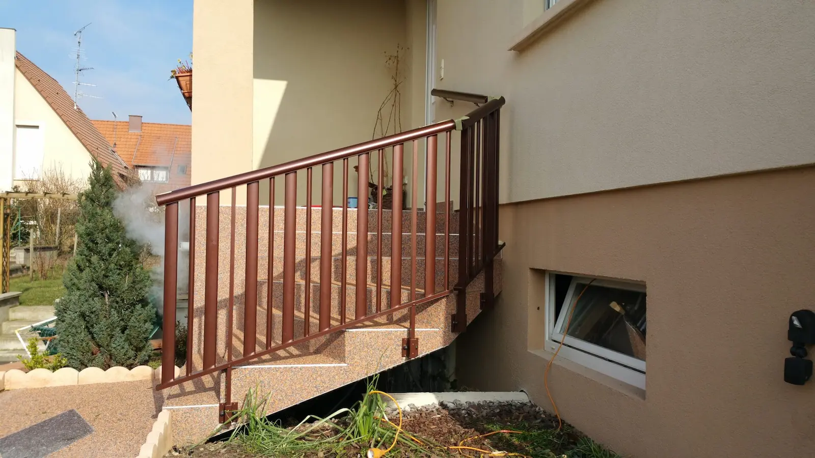 Rampe d'escalier extérieur en aluminium marron avec barreaudage vertical, sécurisant l'accès principal d'une maison individuelle à Plobsheim.